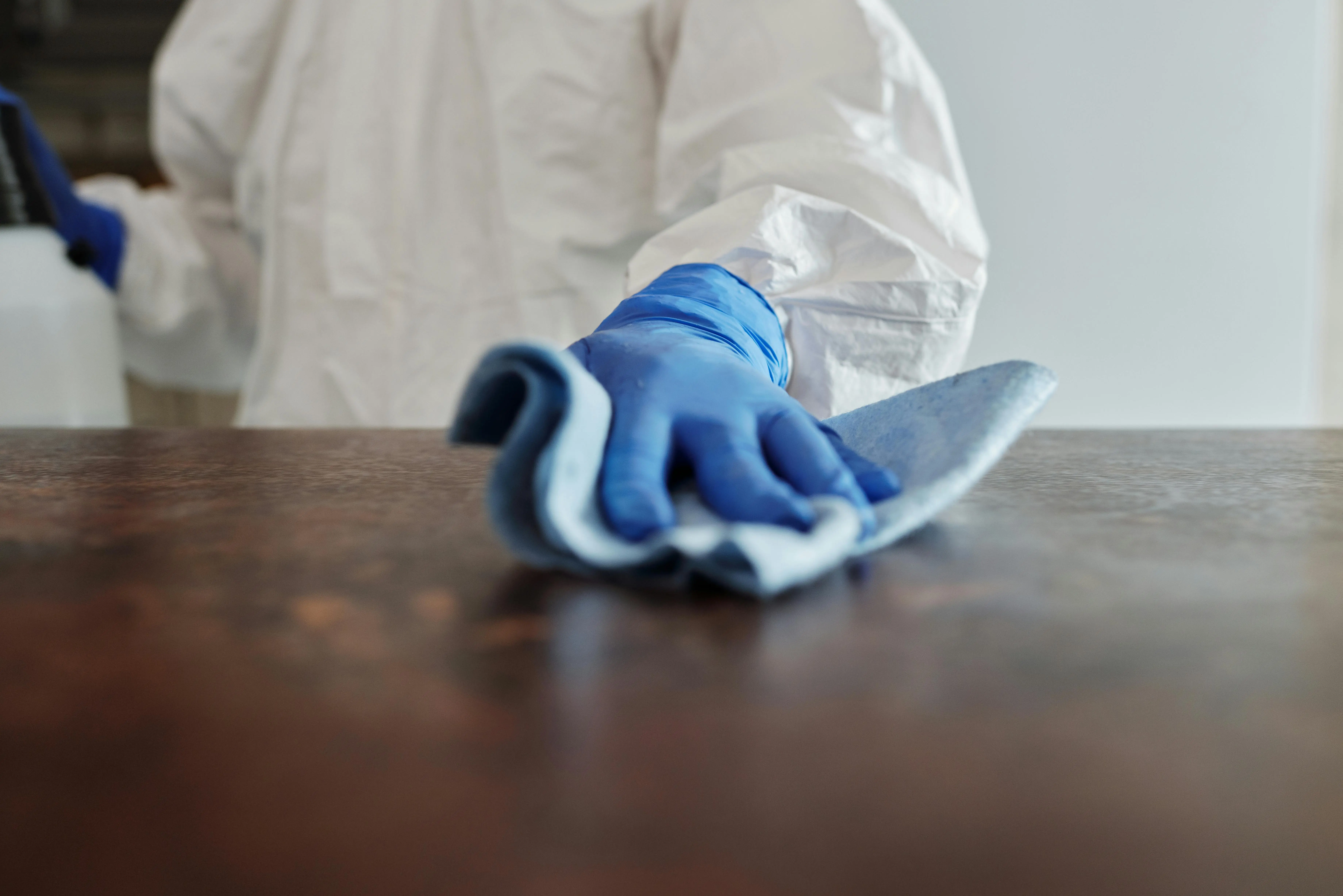 person wearing rubber gloves cleaning a dusty surface with a cloth.